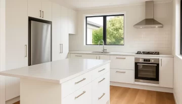 kitchen renovation cost. A digital photograph of a modern, renovated Christchurch kitchen - white cabinetry, stone benchtop, wood flooring, bright natural light